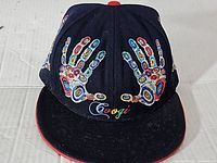 Front view of black Coogi hat with colorful embroidered hands and brand name embroidered under hands.
