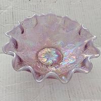 Pink iridescent glass bowl with ruffled edges, embossed leaf pattern, shown from top view.