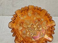 Top and angled view of the iridescent orange vintage carnival glass bowl showing detailed embossed rose floral pattern and ruffled edges.