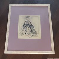 Framed Karen Dupre wall art with pink matting and light wood frame photographed on floor