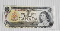 Front side of the 1973 Bank of Canada one dollar bill showing Queen Elizabeth II portrait, coat of arms and bill details with prefix AMM490922.