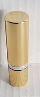 Gold Elizabeth Arden lipstick tube in upright position showing the exterior packaging and logo band.