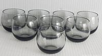 Front view of the set of eight smokey black roly poly glasses arranged in two rows on a plain white surface.