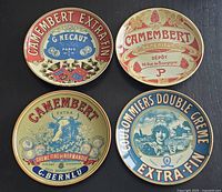 Four ceramic cheese plates arranged on black background showing colorful vintage French cheese labels including Camembert and Coulommiers.
