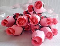 Top view of twelve pink wooden roses bundled together showing flower heads with wrapped plastic packaging.