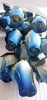Close-up photo of multiple blue and white gradient wooden rose flower heads showing texture and coloring.