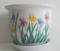 Front and side view of white ceramic jardinière planter decorated with pastel iris flower motifs and attached underplate, showing floral design and overall condition.