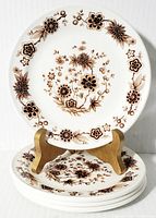 Stacked 4 side plates on a wooden stand showing full plate face with detailed floral design.