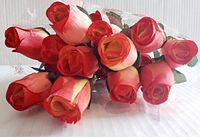 Set of twelve wooden roses in orange-yellow, arranged together showing flower heads and stems.