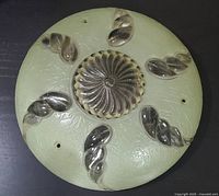Top-down view of the round light shade showing the light green frosted glass base with five clear glass twisted leaf details and a central glass swirl motif.
