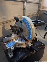 10 inch compound mitre saw with visible blade guard, adjustment angles, and handle in a garage setting