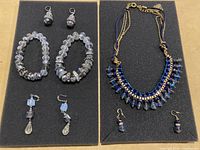 Full view of all jewelry pieces on black foam with two bracelets, two pairs of earrings, necklace, and pair of small matching earrings