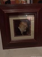 Framed classic portrait artwork of a child with curly blonde hair and ruffled white collar in dark brown wooden frame.