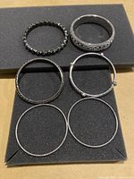 Overview of six bracelets displayed on foam with visible rhinestones and silver-tone finishes, including one with a clasp.