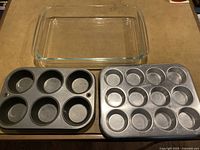Photo of two metal muffin tins (6-cup and 12-cup) with large clear rectangular Pyrex dish placed behind them on a table.
