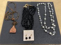 Full lot view with all necklaces and earrings on black background showing details and layout.