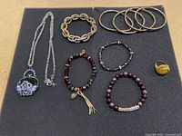 Costume jewelry lot including necklace with floral pendant, five bracelets in various styles, and a yellow stone ring
