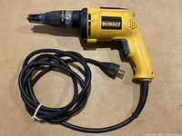 Side view of DeWalt DW255 drywall screw gun with power cord coiled, showing brand label and nosepiece.