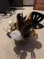Top view showing assorted kitchen utensils within the bucket including wooden spoons, spatulas, whisk and brush.
