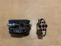 Two bracelets displayed on a beige surface; left bracelet is blue and pearl, right bracelet is red stone bangle.