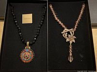 Two Heidi Daus necklaces displayed side by side in black jewelry box.