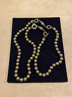 Heidi Daus faux pearl necklace arranged on a flat dark fabric surface showing the entire necklace.