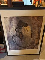Framed Picasso print featuring an abstract nude figure sitting with back visible, dominant brown and beige hues, signed Picasso top left corner.