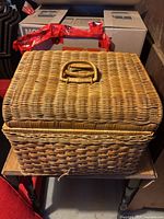 Closed view of large wicker chest showing woven handle on lid and sturdy woven wicker construction.
