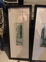 Photo of the first tall framed cityscape painting showing a modern skyscraper with distinctive vertical lines.