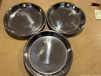Three stainless steel shallow pans arranged side by side on a flat surface.