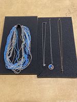 Four necklaces including one multi-strand beaded necklace and three metal chain necklaces with pendants