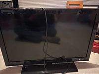 Front view of ViewSonic television with power cord draped over screen, showing the screen, bezel, and pedestal stand.