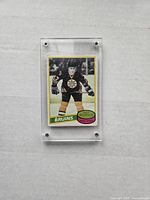 Front view of the Ray Bourque rookie card showing player in Bruins uniform, card name and number visible, encased in protective plastic holder.