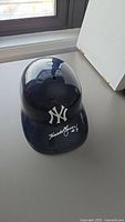 Top front angle view of navy blue Yankees helmet showing logo and signature on brim.