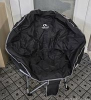 Front view of black padded foldable camping chair with Canadian Shield logo and rounded bucket seat style.