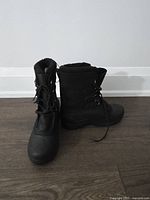 Front view of the pair of black winter boots with laces and cardboard inserts inside showing new condition