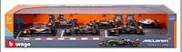 Photo of the full boxed set showing six McLaren Formula 1 cars at 1:43 scale, in orange and black.