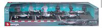 Wide shot of the unopened BBURAGO box containing six 1:43 scale Mercedes Benz Formula 1 die cast cars arranged in a line.