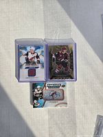 Front view of three Clayton Keller hockey cards including rookie jersey and Artifacts Aurum card.