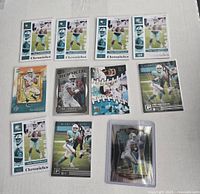 Top-down view of 12 Tua Tagovailoa rookie football cards arranged on white background, showing various brands and card designs focused on NFL Miami Dolphins quarterback.