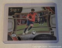 Front photo of the Lamine Yamal 2023-24 Panini Select rookie card in protective sleeve showing Yamal in Spanish national team uniform, with Select and FIFA logos.