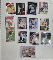 Top-down view of 13 baseball cards laid out on a white surface showing various MLB stars including Mike Trout, Mookie Betts, and Aaron Judge.