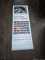 Full length view of new vinyl NHL advertising banner showing entire design including Scotiabank and NHL logos, VISA cards and slogan text on wooden floor.