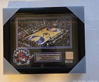 Frontal view of the commemorative frame showing the basketball court photo, logo, plaque, and the embedded piece of hardwood floor.
