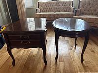 Rectangular end table with drawer next to oval end table on hardwood floor in living room setting