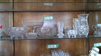 Shelf display showing assorted lead crystal bowls, a stemmed dessert bowl, and candy dishes with intricate pinwheel and floral cuts.