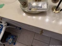 Photo of a bathroom countertop with a Nitrex ceramic toothbrush holder, razors in plastic case, and part of the curling iron visible