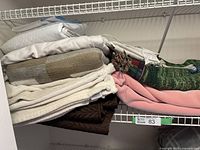 Stack of assorted blankets and throws on a wire shelf