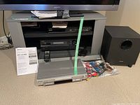 Photo showing the Sony Blu Ray player on the shelf above the Onkyo home theatre receiver and Panasonic DVD player in front, along with cables and the Onkyo subwoofer on the floor.