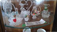 Glass shelf with multiple spun glass ornaments including swans, miniature basket with fruit, handled jug, and Victorian basket.